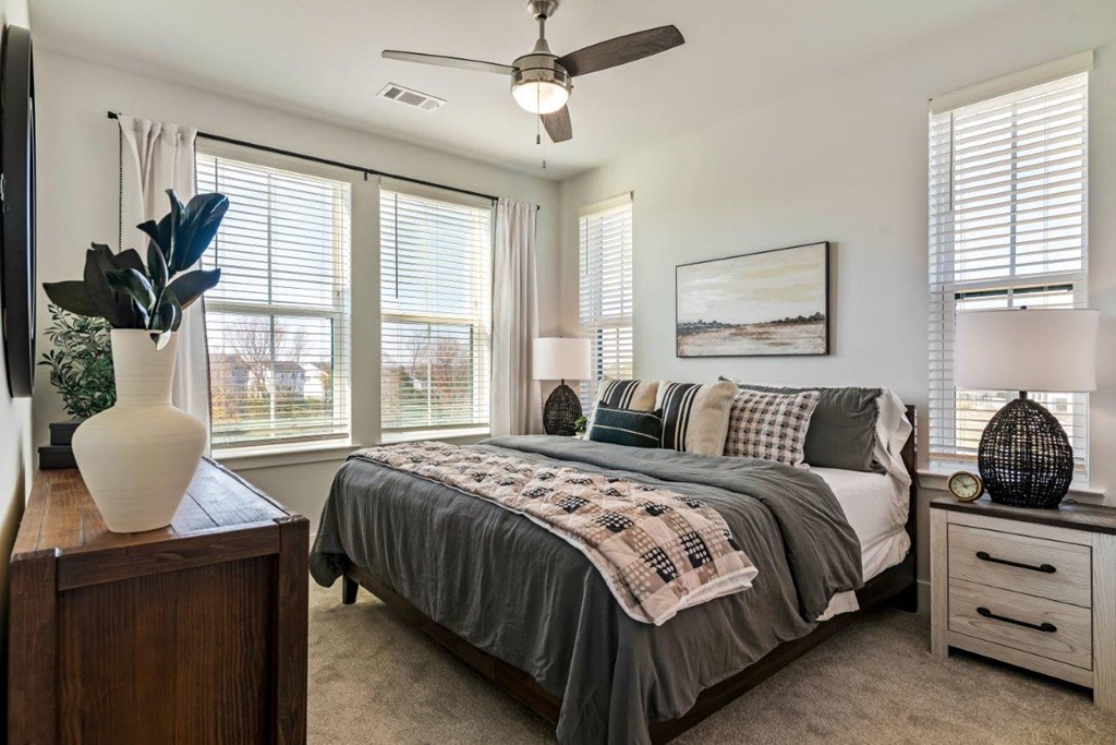 A bedroom with a bed, a dresser, and a ceiling fan.