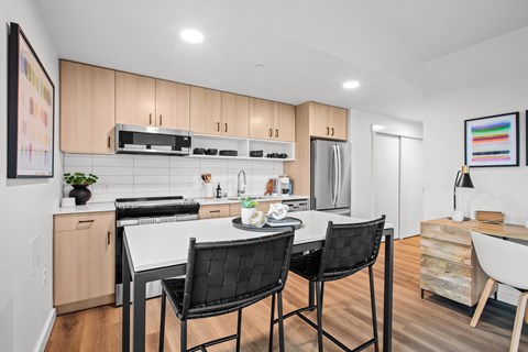 a kitchen with wooden cabinets and a white island with black chairs