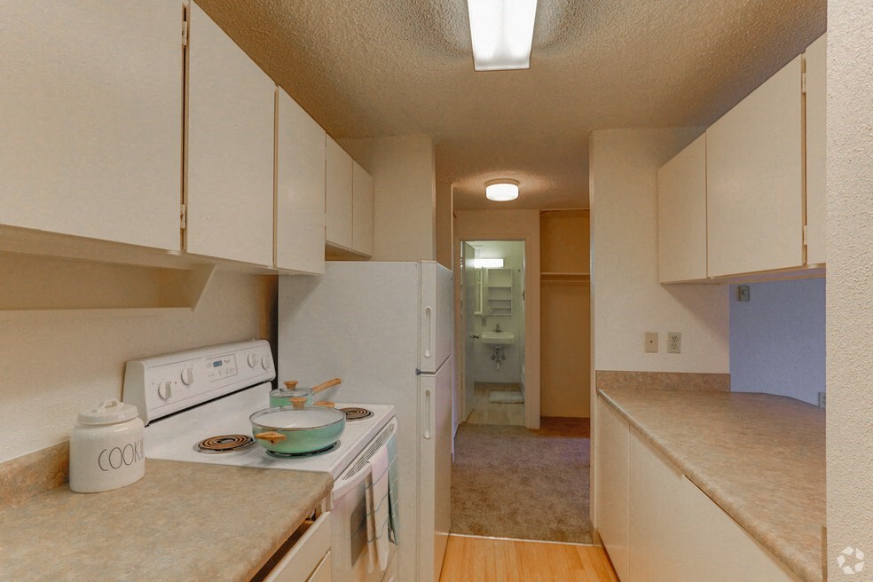 an empty kitchen with white appliances and white cabinets