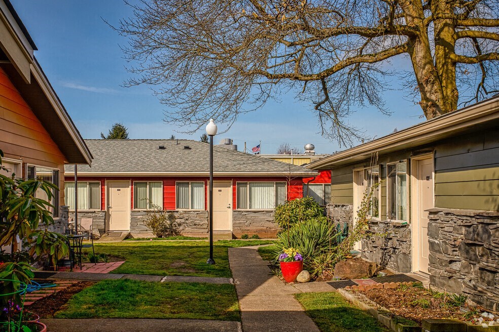 a courtyard between two houses with a sidewalk and a tree