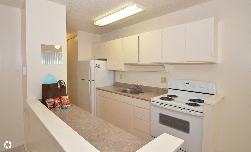 an empty kitchen with white appliances and white cabinets