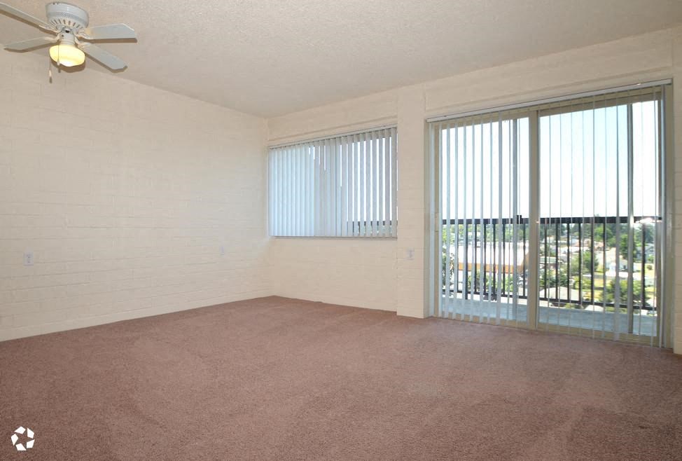 an empty living room with windows and a ceiling fan