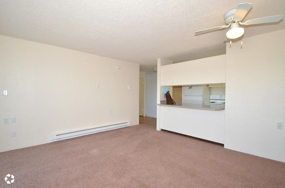 an empty living room and kitchen with a ceiling fan