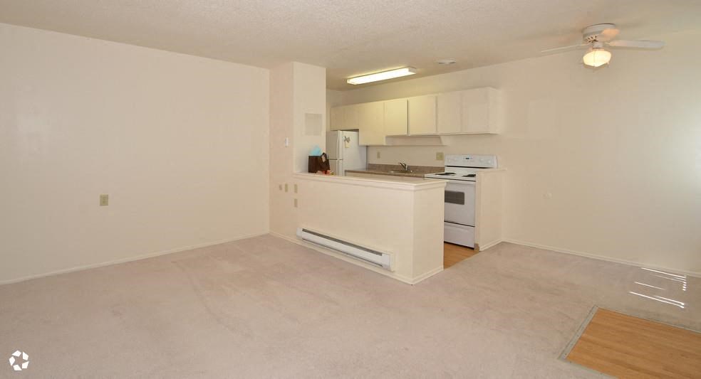 an empty living room and kitchen with a stove and refrigerator