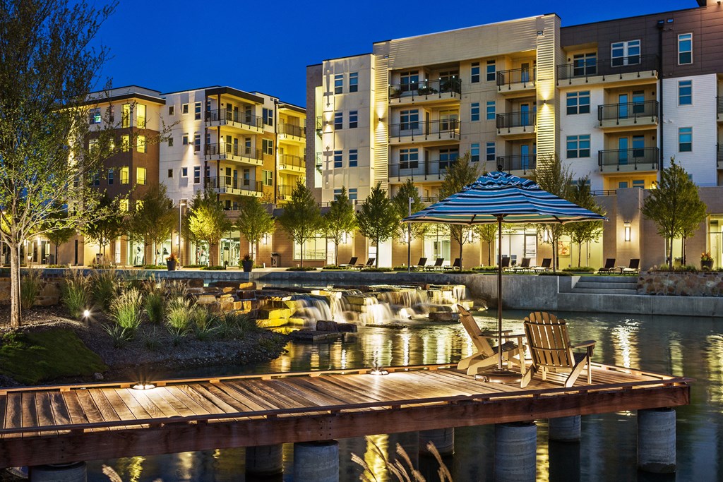 a dock on the water at night with buildings in the background
