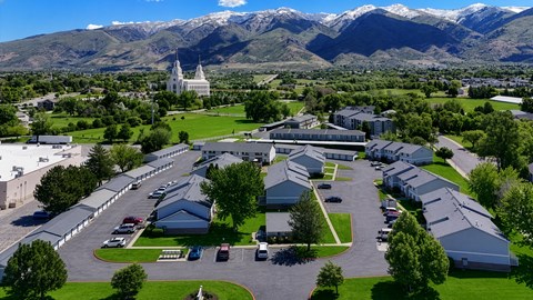 A large white building with a green lawn in front and mountains in the background.