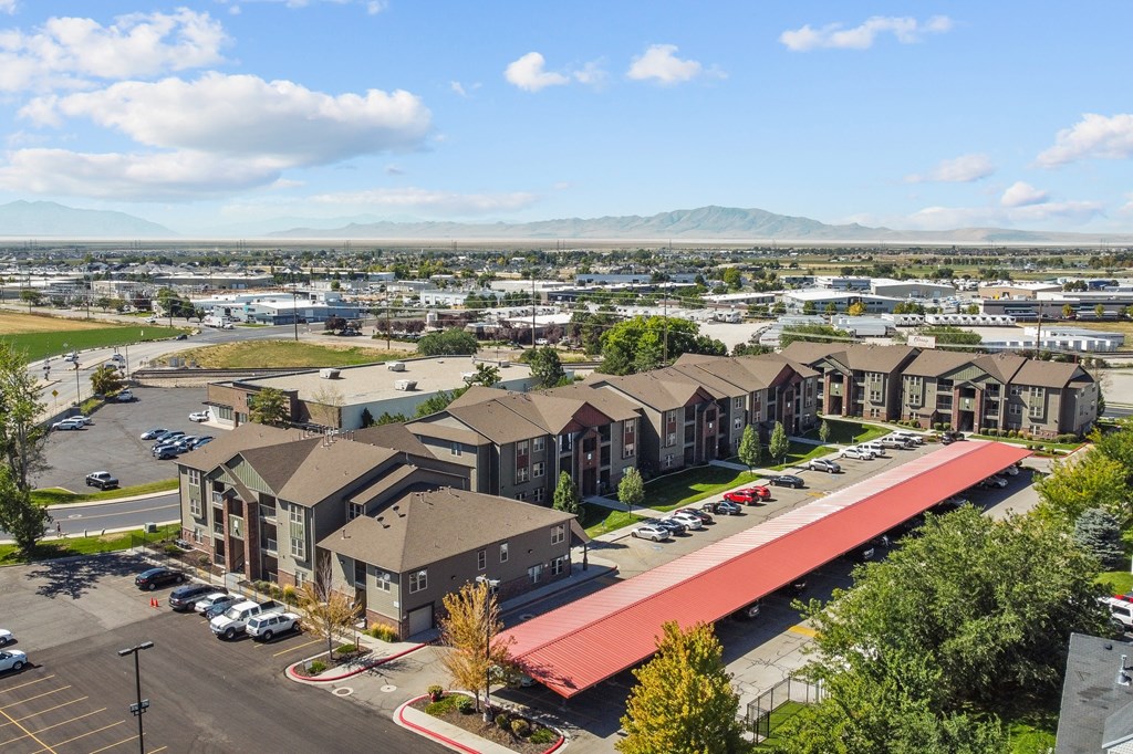 an aerial view of a row of apartment buildings with a parking lot and mountains in the background
