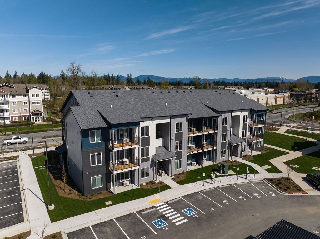 A large grey building with a parking lot in front of it.