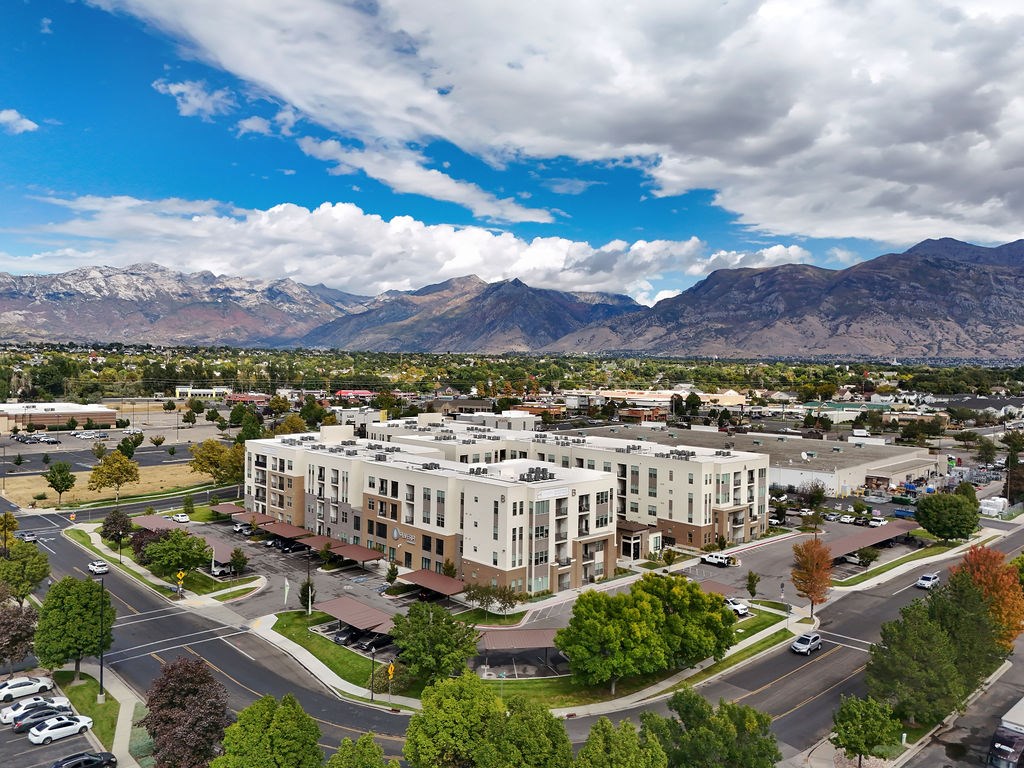 Alvera at the Meadows  large building is surrounded by trees and mountains are in the background.