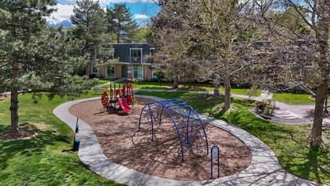 A playground with a blue swing set and red slides.
