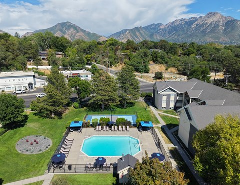 A pool surrounded by a fence and chairs with mountains in the background.