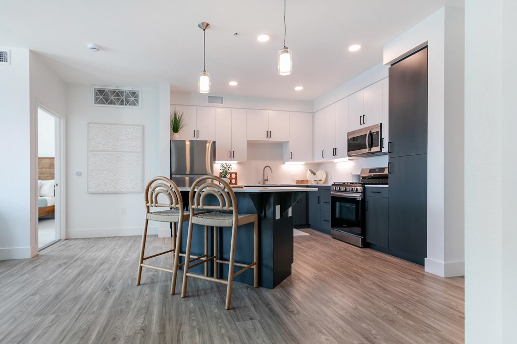 A modern kitchen with a bar stool and a dining table.
