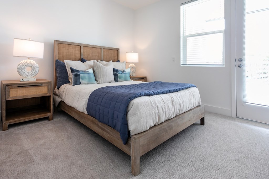 A bedroom with a large bed and two lamps on side tables.