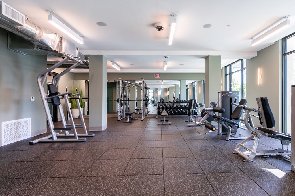 A gym with a variety of equipment including treadmills, weights, and exercise machines.