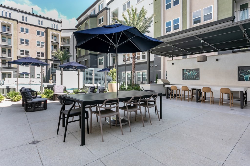 A patio with a table and chairs under a blue umbrella.