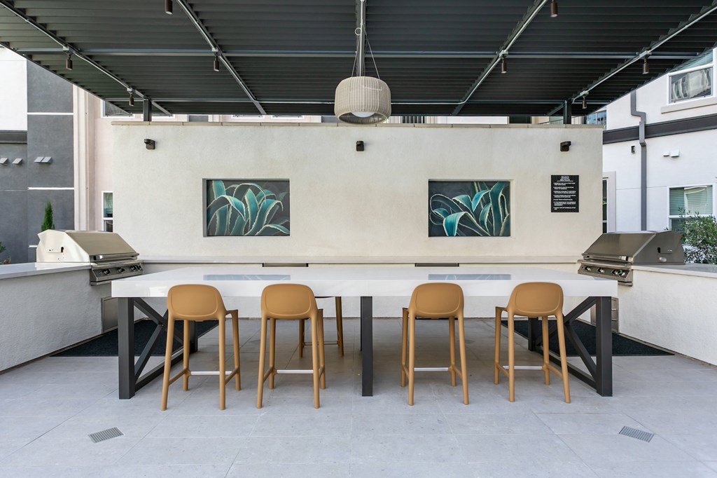 A white table with four chairs in front of a wall with two paintings on it.