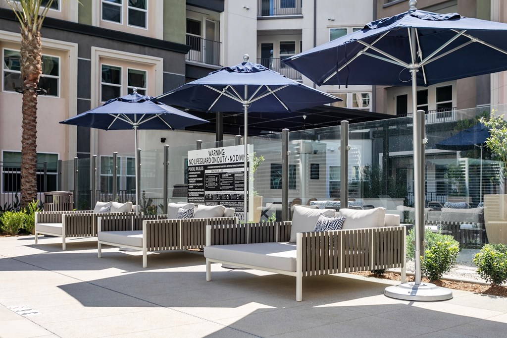 A patio with white furniture and blue umbrellas.