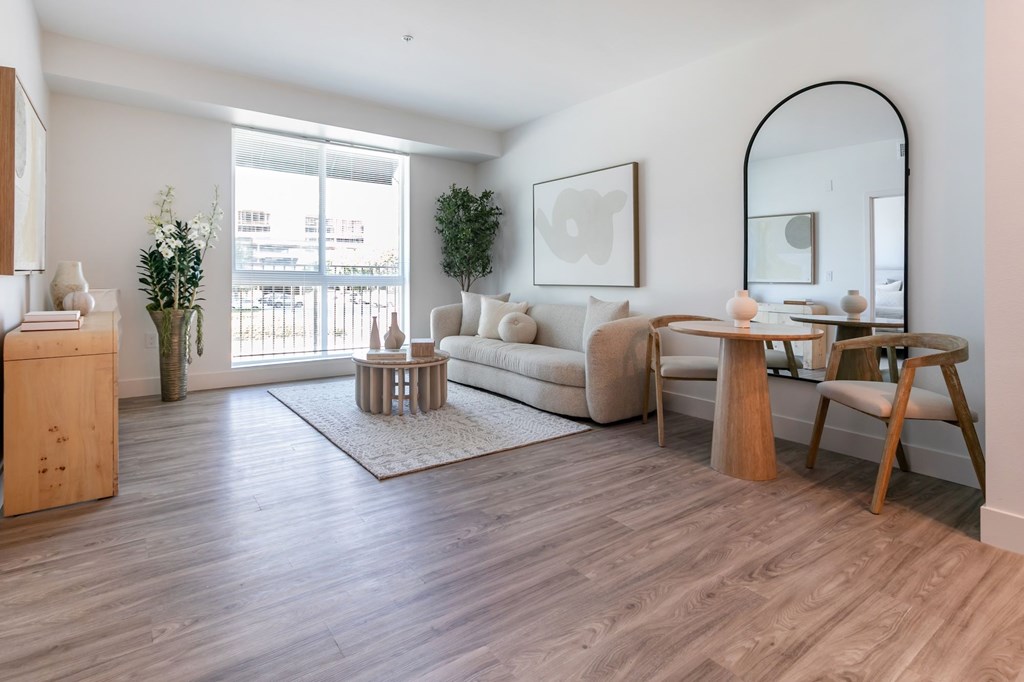 A living room with a white sofa, wooden coffee table, and a mirror on the wall.