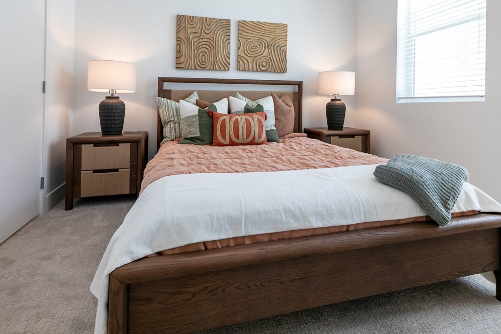 A bedroom with a large bed and two lamps.