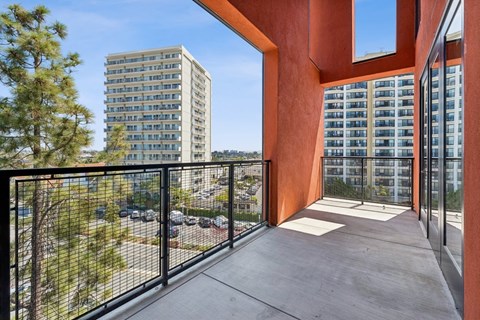 A balcony with a black railing and a view of a parking lot and a building.