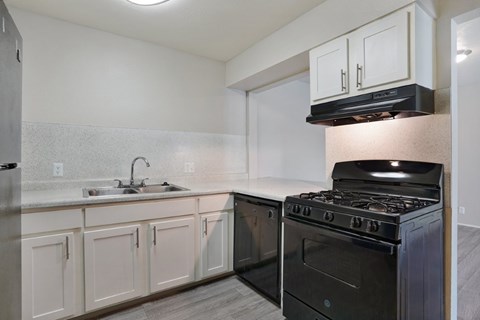 A kitchen with a black stove and white cabinets.