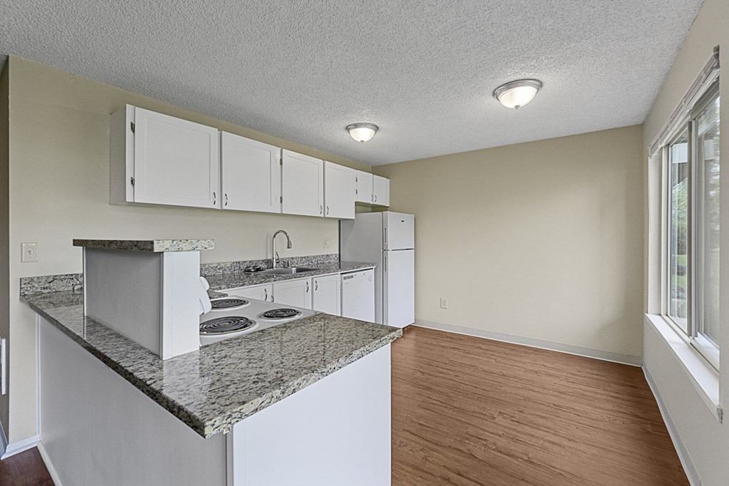 an empty kitchen with white cabinets and a counter top