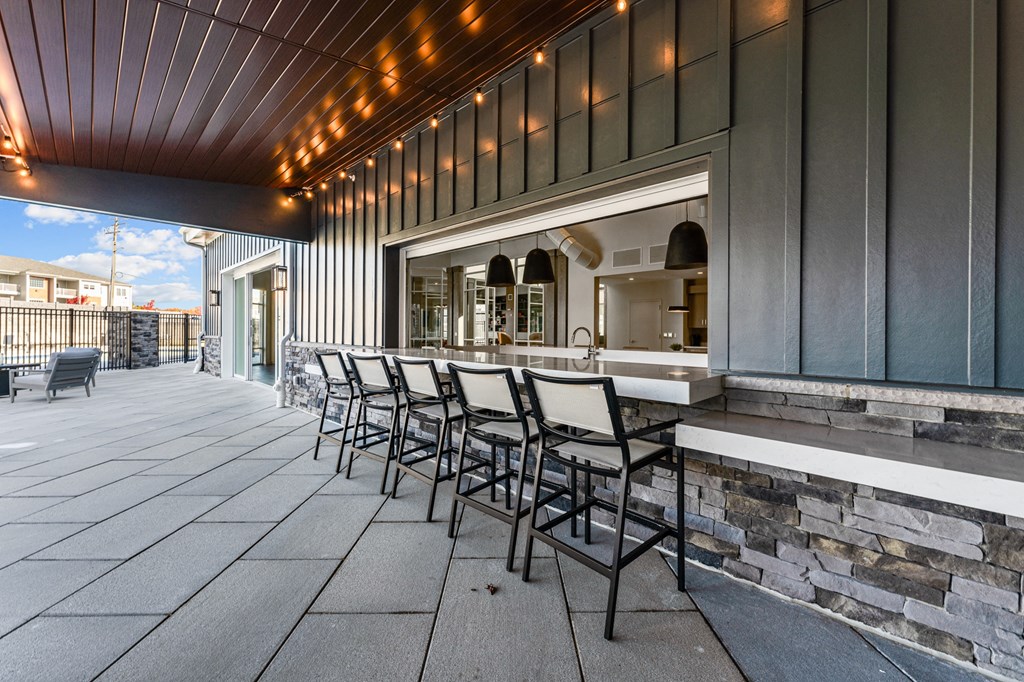 a patio with a bar and chairs in front of a building