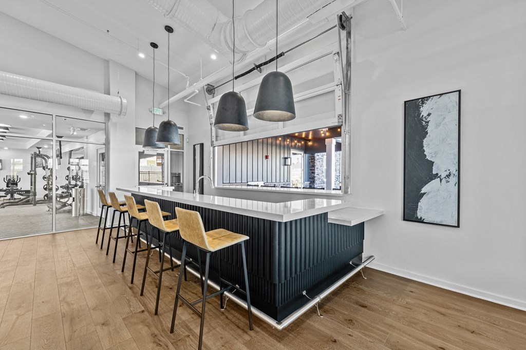a long bar with chairs in a restaurant with white walls and wood floors