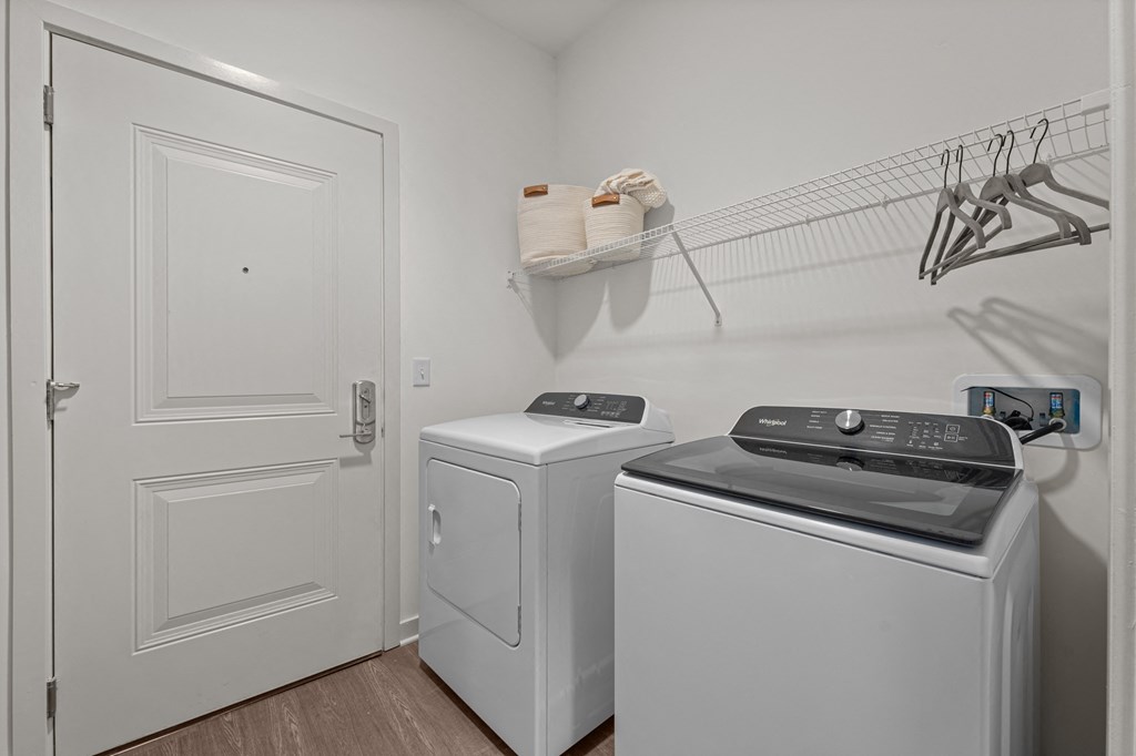 a laundry room with two washers and dryers and a door to a closet