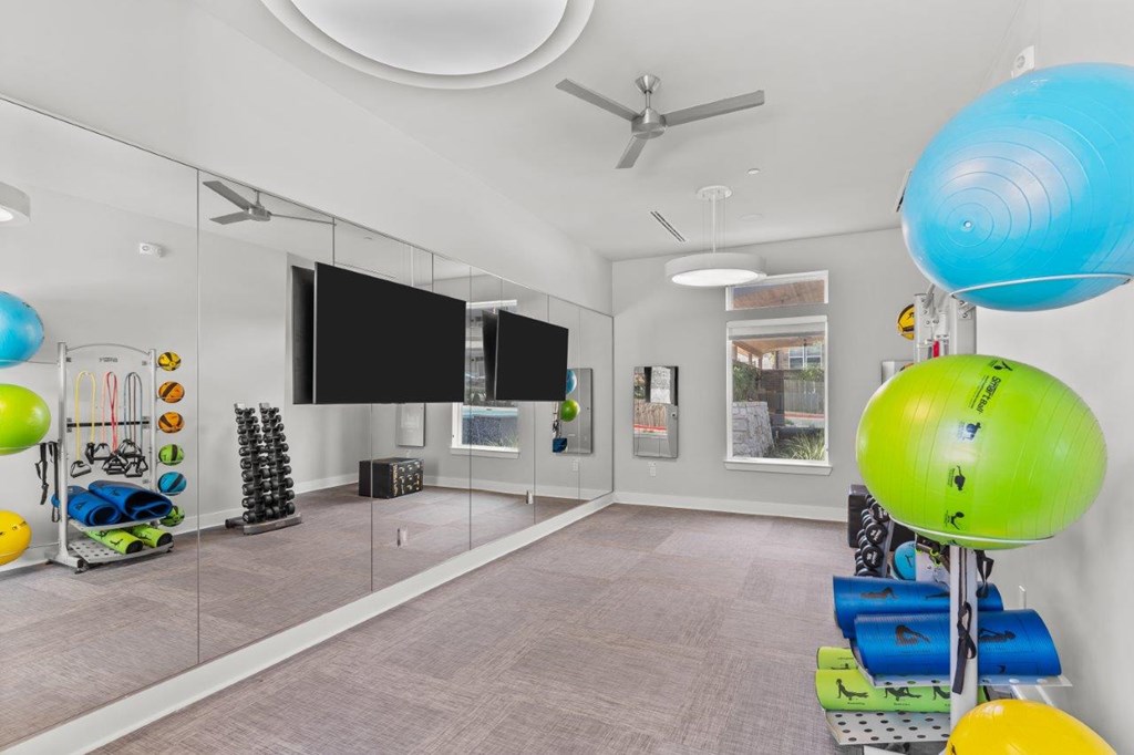 A room with a mirror, a fan, and exercise equipment.