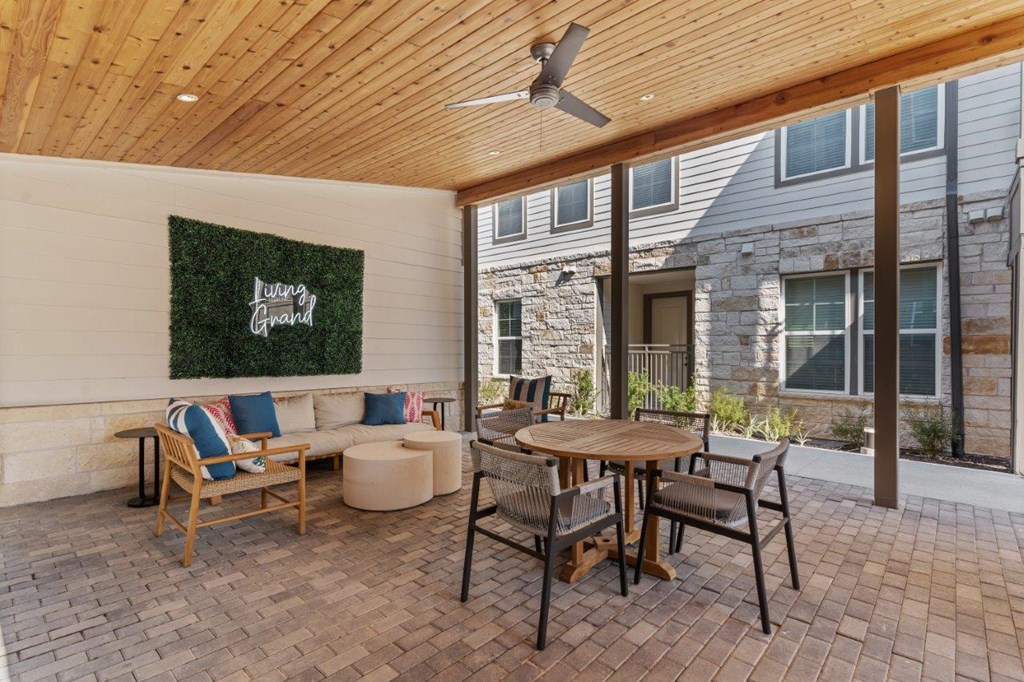 A patio with a wooden table and chairs and a green wall with the word