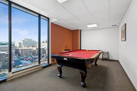 A pool table in a room with a view of the city.