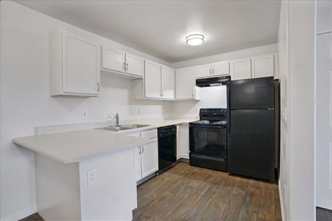 A kitchen with black appliances and white cabinets.