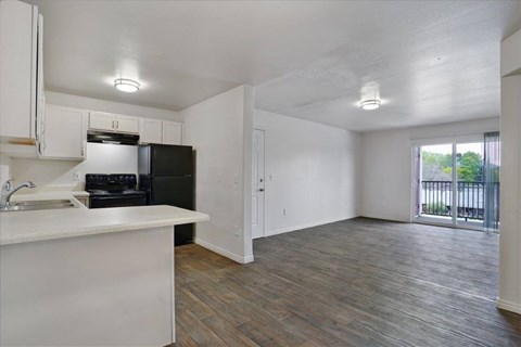 A kitchen with white cabinets and a black fridge.