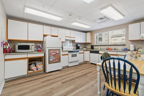 A kitchen with white cabinets and wooden floors.