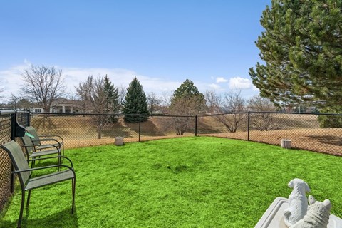 A backyard with a green lawn and a bench.