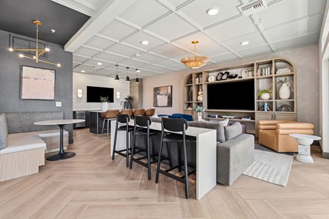 A modern living room with a grey sofa, a wooden floor, and a white ceiling.