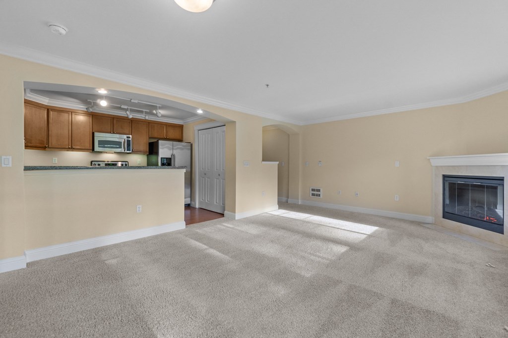 a living room with a fireplace and a kitchen in the background