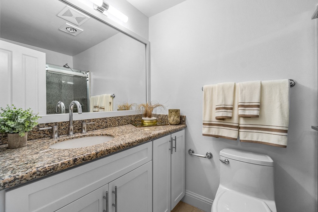 a bathroom with white cabinets and a granite countertop