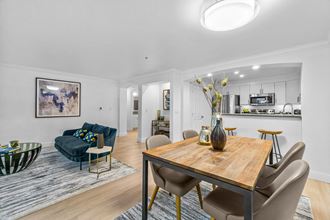 a dining area with a wooden table and chairs and a couch in the background - Photo Gallery