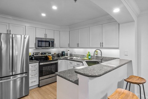 a white kitchen with granite counter tops and stainless steel appliances