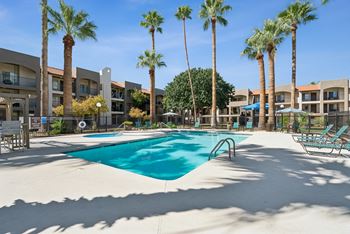 A swimming pool surrounded by palm trees and lounge chairs.