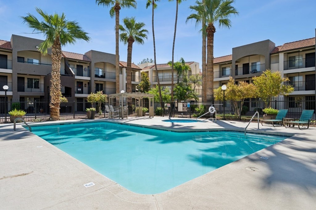 Casa Bella  A swimming pool surrounded by palm trees and apartment buildings.