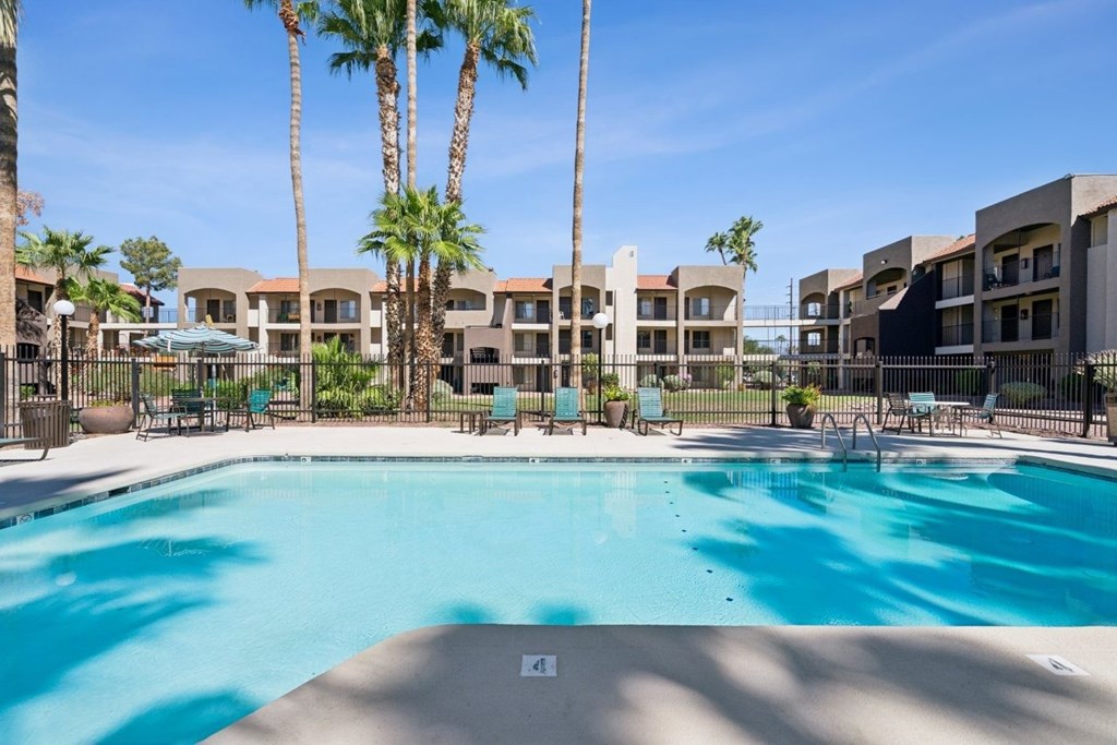 Casa Bella  A swimming pool surrounded by palm trees and apartment buildings.