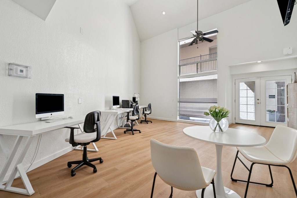 A white desk with a computer and chair in a room with a balcony.