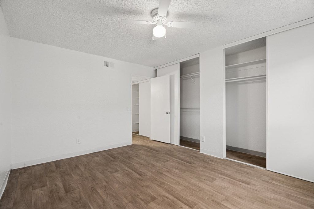 Empty room with wooden flooring and white walls.