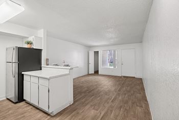A kitchen with white cabinets and a black fridge.