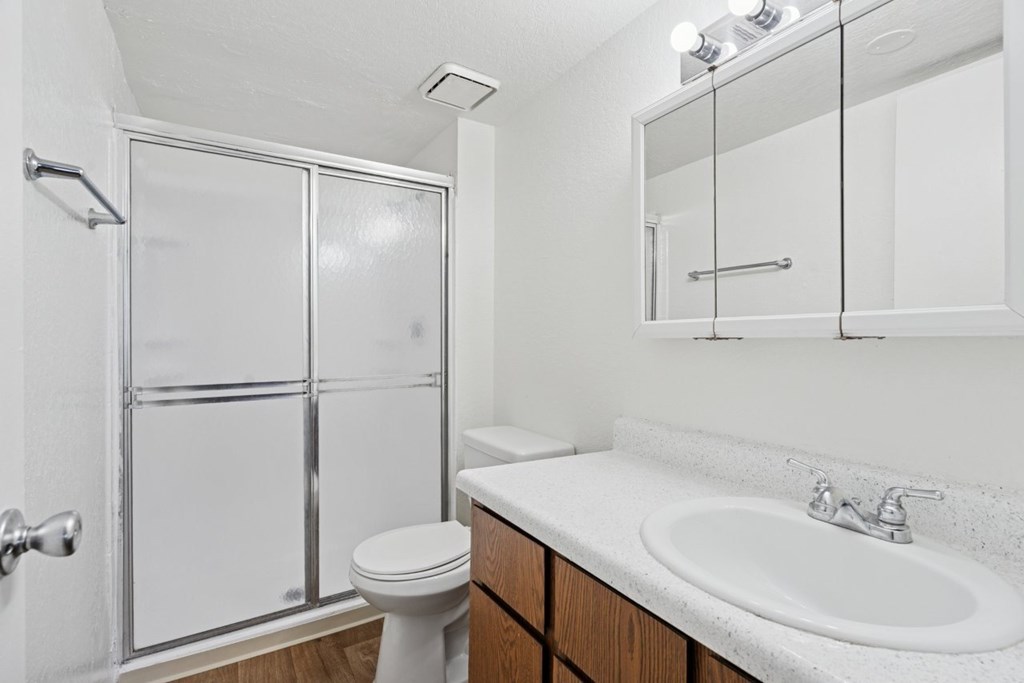 Casa Bella bathroom with wood cabinets and white countertops with toilet and tub
