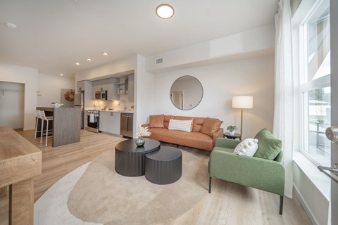 A living room with a green couch and a round mirror on the wall.