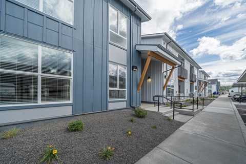 A modern building with a blue exterior and a gravel area in front.